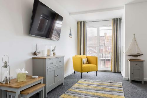 a living room with a yellow chair and a desk at Just Beachy - Moments from Hamworthy Beach and Park in Poole