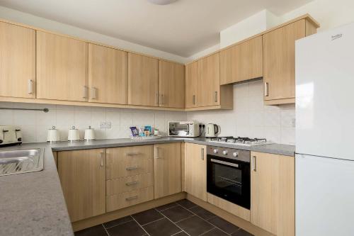 a kitchen with wooden cabinets and a white refrigerator at Just Beachy - Moments from Hamworthy Beach and Park in Poole