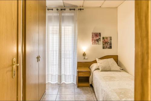 a small bedroom with a bed and a window at Hostal La Barretina in Figueres