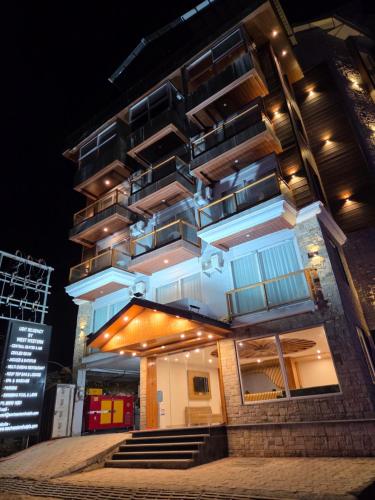 a tall building with lights on it at night at The Udit By West Western - Central Heated and Air Cooled - River View & Roof Top cafe & Bar in Kasol