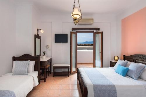 a hotel room with two beds and a desk and a bathroom at Astir Thira Hotel in Fira
