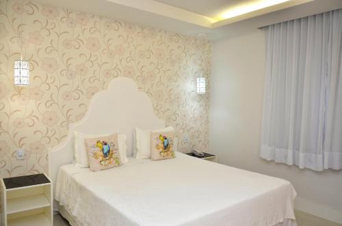 a bedroom with a white bed with two pillows at Hotel Girassol in Penedo