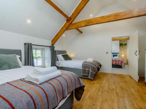 two beds in a room with wooden floors and ceilings at 4 Bed in Llandysul oc-89422 in Cwm-pengraig