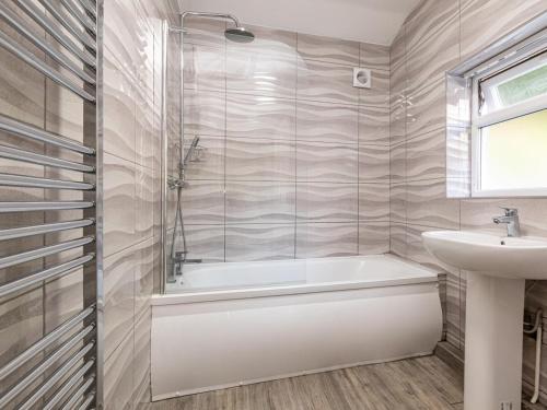 a bathroom with a bath tub and a sink at 4 Bed in Bala oc-75288 in Llandderfel