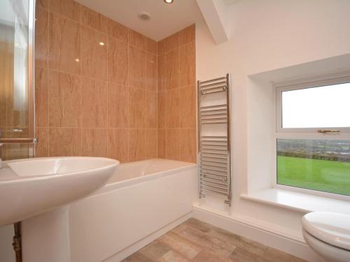 a bathroom with a sink and a tub and a window at 4 Bed in Llandysul oc-66640 in Llandysul