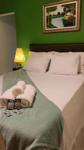 a green bedroom with a bed with towels on it at Pousada Raízes do Cipó in Serra do Cipo