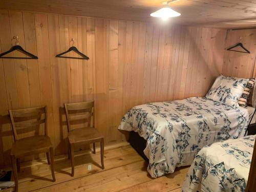 two beds and chairs in a room with wooden walls at Swiss Mountain Chalet in Saxeten