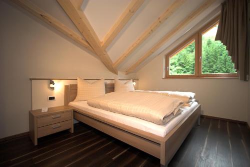 a bedroom with a bed and a window at Residence Rosengarten - Alpenglühen zum Anfassen, inklusive Guestpass in Tires