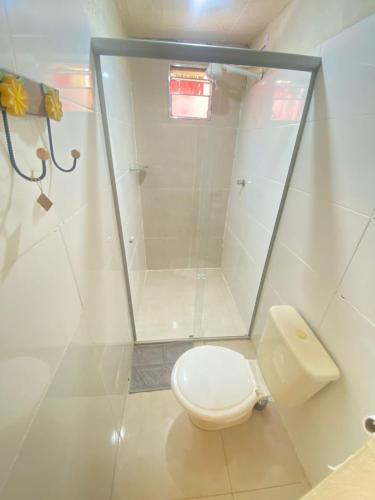 a white bathroom with a toilet and a shower at Pousada Raízes do Cipó in Serra do Cipo