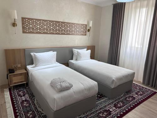 a hotel room with two beds and a rug at Lazgi Boutique & Spa Hotel in Khiva