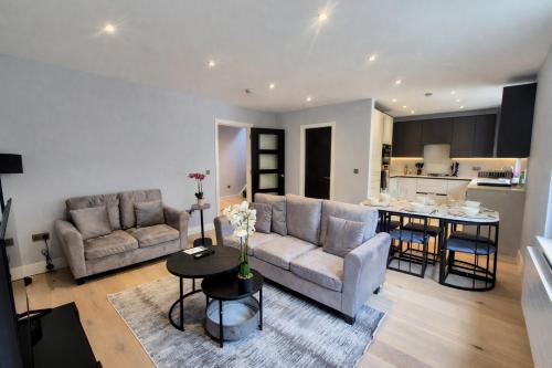 a living room with two couches and a kitchen at Stylish Three Bedroom Ensuite Duplex Apartment in West Hampstead in London