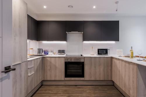 a kitchen with black cabinets and white counter tops at Little Sea - Moments from Waterfront Restaurants in Poole