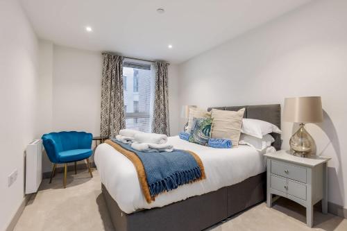 a bedroom with a large bed and a blue chair at Little Sea - Moments from Waterfront Restaurants in Poole