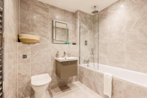 a bathroom with a toilet and a sink and a tub at Little Sea - Moments from Waterfront Restaurants in Poole