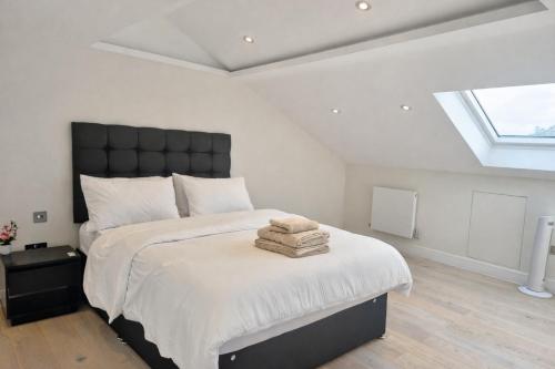 a bedroom with a large bed with a black headboard at Stylish Three Bedroom Ensuite Duplex Apartment in West Hampstead in London