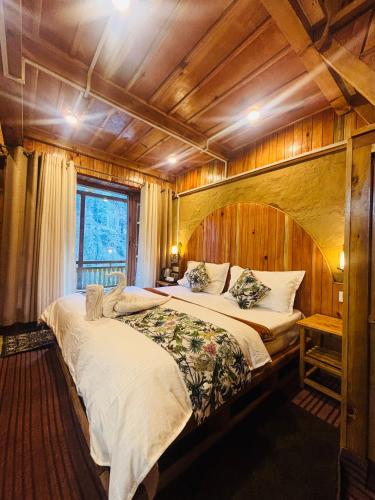 a bedroom with two beds in a room with wooden walls at Mountain Nest Stay in Jibhi