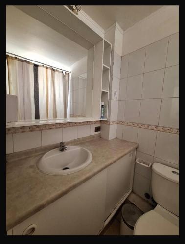 a bathroom with a sink and a toilet and a mirror at Departamento COPAYAPU in El Cerrillo