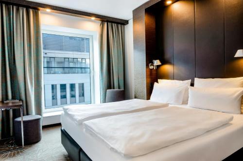 a bedroom with a large white bed with a window at Motel One Leipzig-Augustusplatz in Leipzig