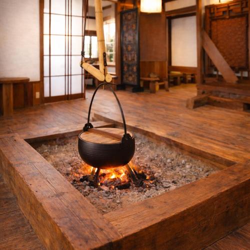 a wok is cooking over a fire in a room at 里や 糸島 川遊び Bbq 花火を楽しむ古民家1棟貸し in Itoshima