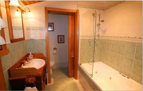 y baño con bañera, lavamanos y ducha. en Westbury Gingerbread Cottages, en Westbury