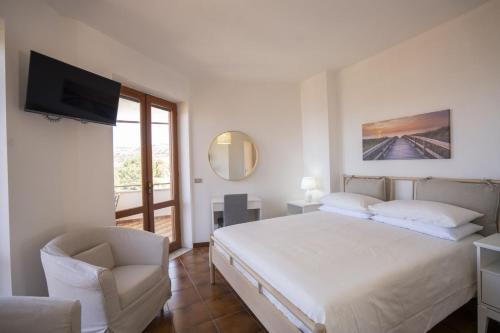 a bedroom with a bed and a chair and a television at Villa Acquamarina, Family apartments with pool - 300 meters from the beach in Santa Maria