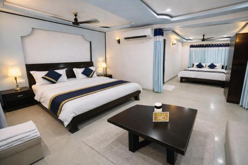 a bedroom with a bed and a table and a couch at Hotel Ashoka Mountabu in Mount Ābu