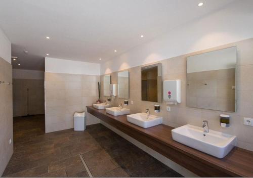 a bathroom with three sinks and two mirrors at Camping Bergkristall in Moso