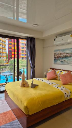 a bedroom with a large yellow bed with two stuffed animals on it at PB329 Phuket's best oceanfront studio in Ban Mai Salae