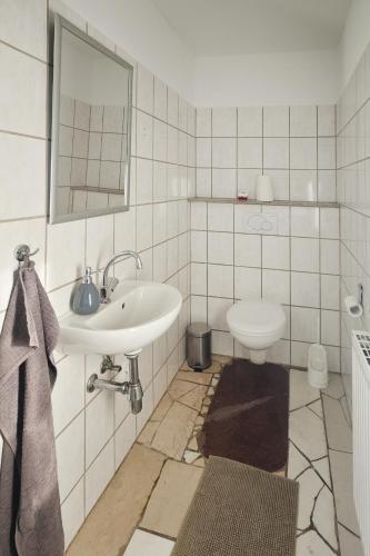 a white bathroom with a sink and a toilet at Apartment 1 in Diepholz