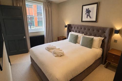 a bedroom with a large bed with white sheets at Macbeths Corner - Luxury Apartment with Private Parking in Stratford-upon-Avon