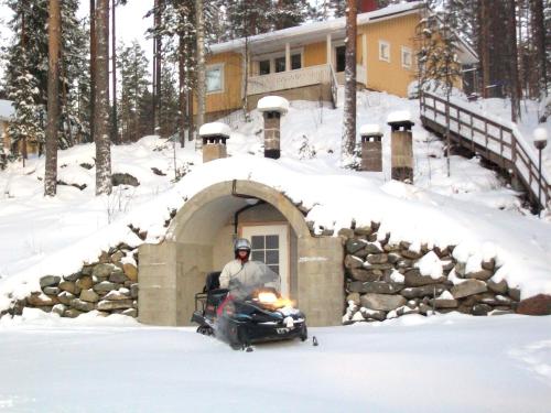 a man riding a snowmobile in a snow garage at Lake Cottage Jänisvaara in Kolinkylä