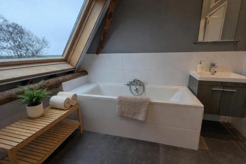 a bathroom with a bath tub and a sink at Ballumerhoeve Skip lodge in Ballum