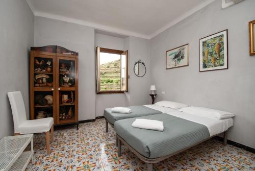 a bedroom with two beds and a chair and a window at Casa Di Mezzo by Arbaspàa in Manarola