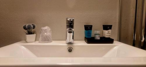 a white bathroom sink with a faucet and products on it at Vardø Hotel by Destination Vardø in Vardø