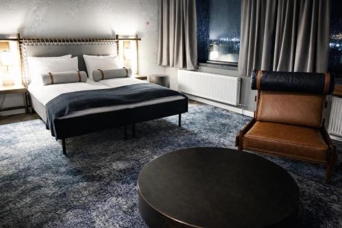 a bedroom with a bed and a chair and a table at Vardø Hotel by Destination Vardø in Vardø