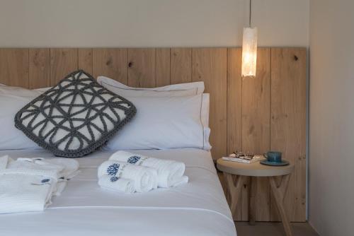 a bedroom with a white bed with towels on it at Sifnos House - Rooms and SPA in Kamarai