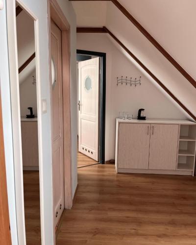an attic room with a staircase leading to a room with a door at SKiPER Dębki in Dębki