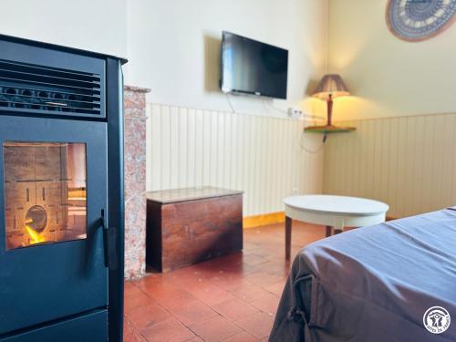 a room with a fireplace with a bed and a table at Le Refuge in Liernais