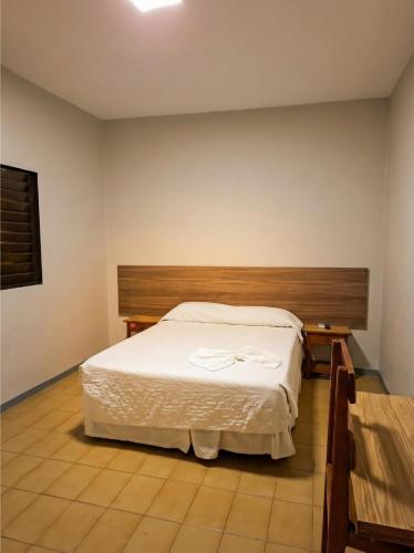 ein Schlafzimmer mit einem weißen Bett und einem hölzernen Kopfteil in der Unterkunft Hotel Brivanna in Campo Grande