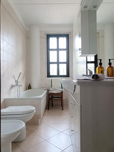 a white bathroom with a tub and a toilet and a sink at La Casa del Merlo in Rodello