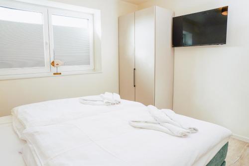a white bed in a room with a tv at Küste33 34 in Tossens