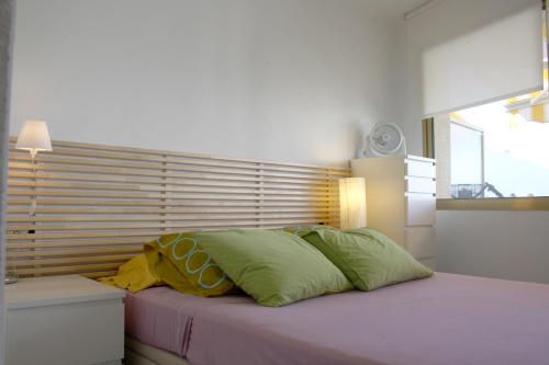 1 dormitorio con 1 cama con almohadas verdes y amarillas en Synergie SI14 - Sol Daurat, en Cambrils