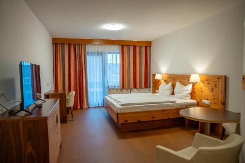 a bedroom with a bed and a table and a television at Braugast Kreuz in Frastanz