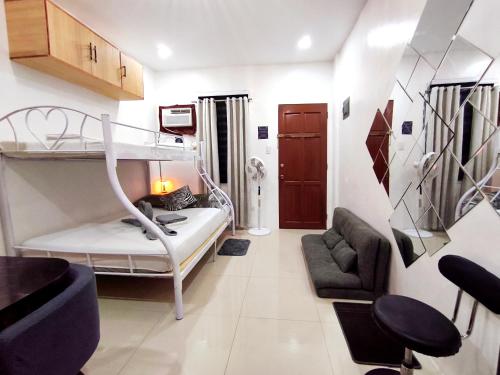 a small room with a bunk bed and a couch at SNOW Studio Apartment - Near Clark International Airport in Mabalacat