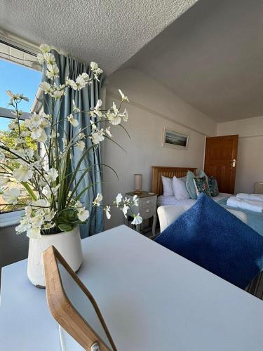 a room with two beds and a table with a vase of flowers at Rhos on sea home in Llandrillo-yn-Rhôs
