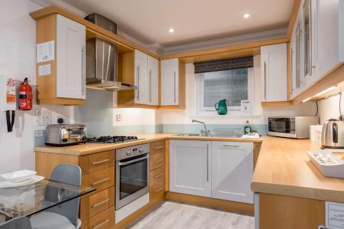 a kitchen with wooden cabinets and white appliances at Magnolia House - Beautiful Townhouse in Old Town Poole in Poole