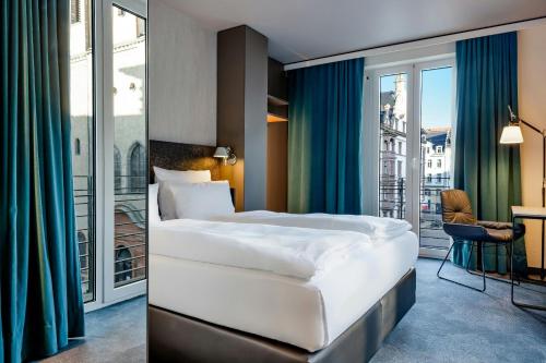 a hotel room with a bed and a balcony at Motel One Leipzig-Nikolaikirche in Leipzig
