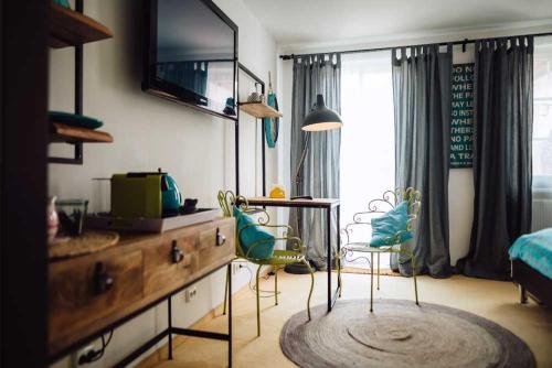 a bedroom with a desk with a television and chairs at DAS STERN - Rooms - Self Check-In in Sankt Gilgen