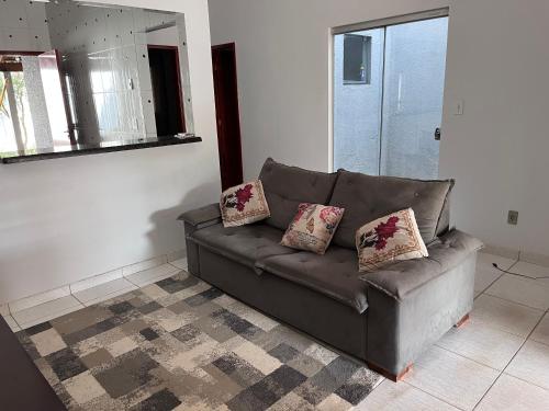 a brown couch in a living room with two pillows at Casa jardim fonte nova in Goiânia