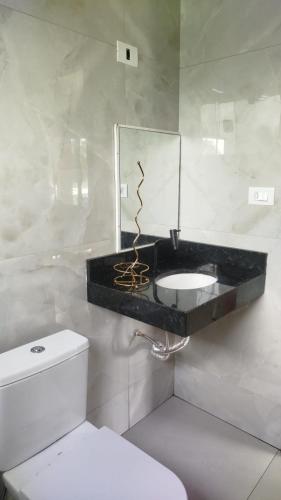 a bathroom with a sink and a mirror and a toilet at Complete Chácara Pool, WiFi 5min Thermas in São Pedro